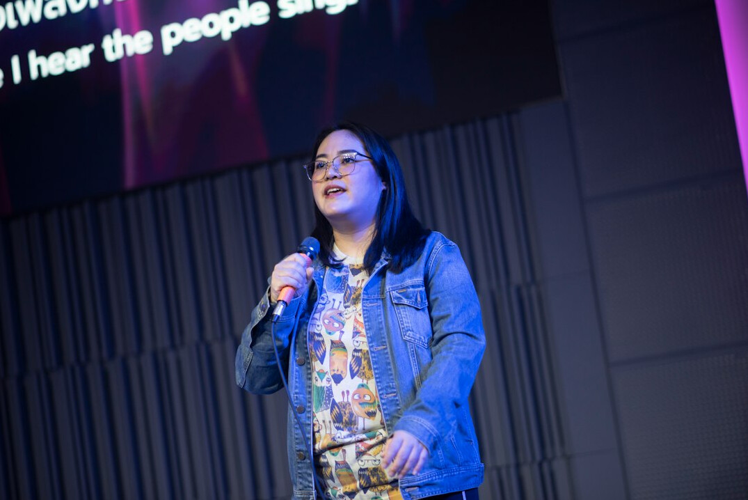 Speaker presenting on stage in front of a screen